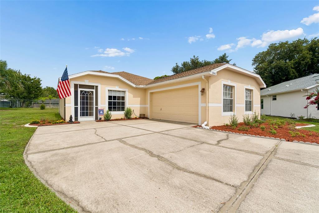 A single-story house with a beige stucco exterior, a two-car garage, and a concrete driveway — 20942 SUNSWEET COURT, LAND O LAKES, FL