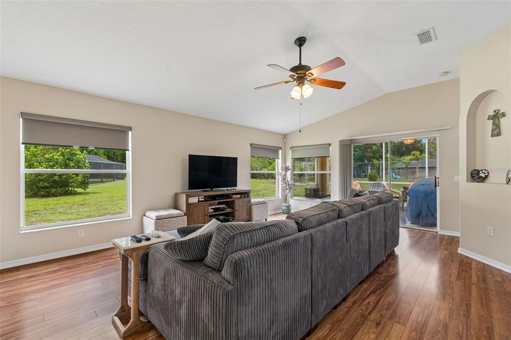 A living room features a grey sectional sofa, wood flooring, and a ceiling fan — 20942 SUNSWEET COURT, LAND O LAKES, FL