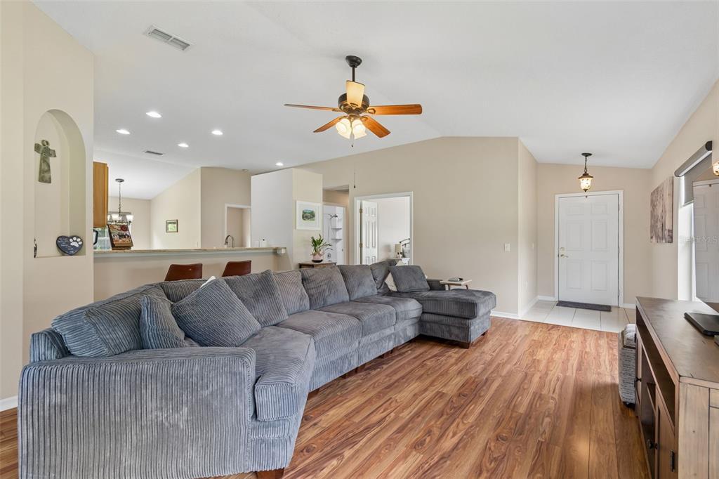 A living room with wood-look flooring, a large gray sectional sofa, and a ceiling fan — 20942 SUNSWEET COURT, LAND O LAKES, FL
