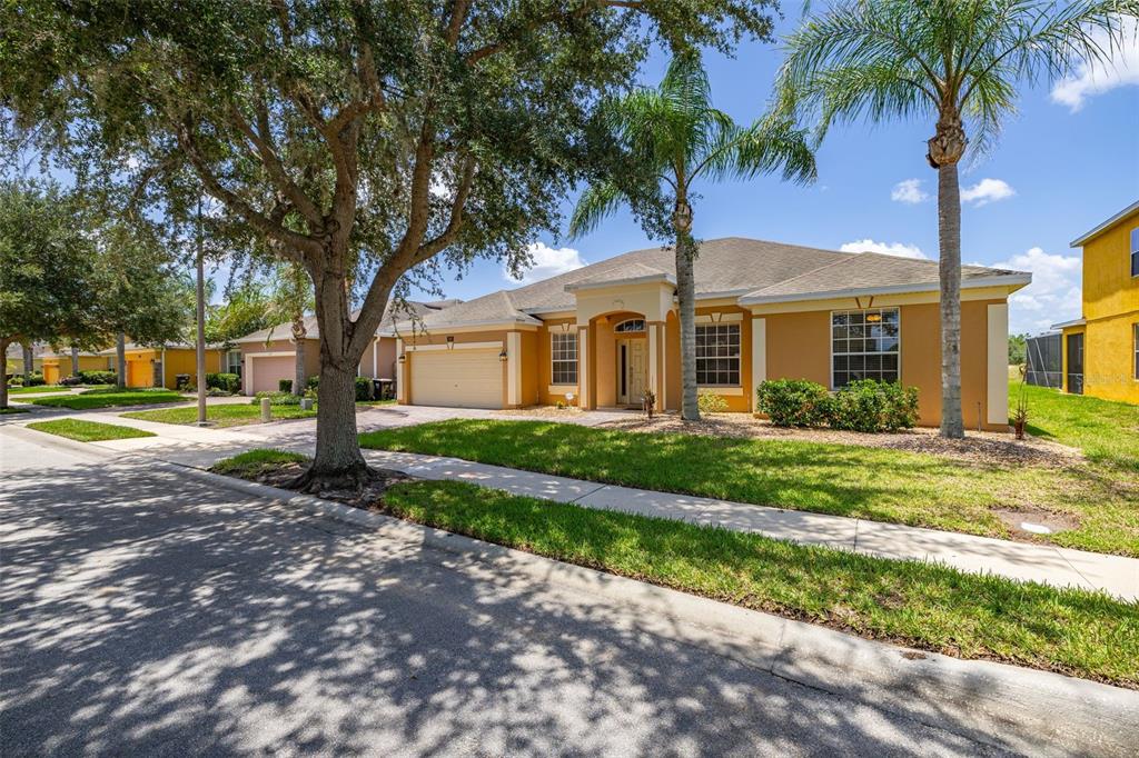 A single-story tan house with a two-car garage and a palm tree in the yard — 349 YELLOW SNAPDRAGON DRIVE, DAVENPORT, FL