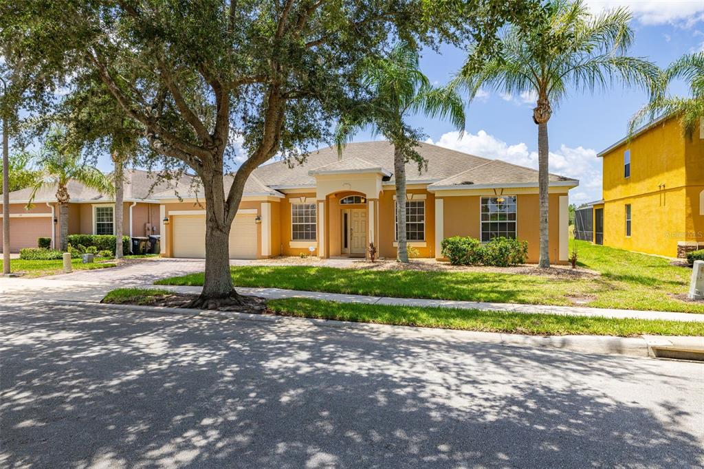 A single-story suburban house with a tan stucco exterior, a two-car garage, and palm trees — 349 YELLOW SNAPDRAGON DRIVE, DAVENPORT, FL