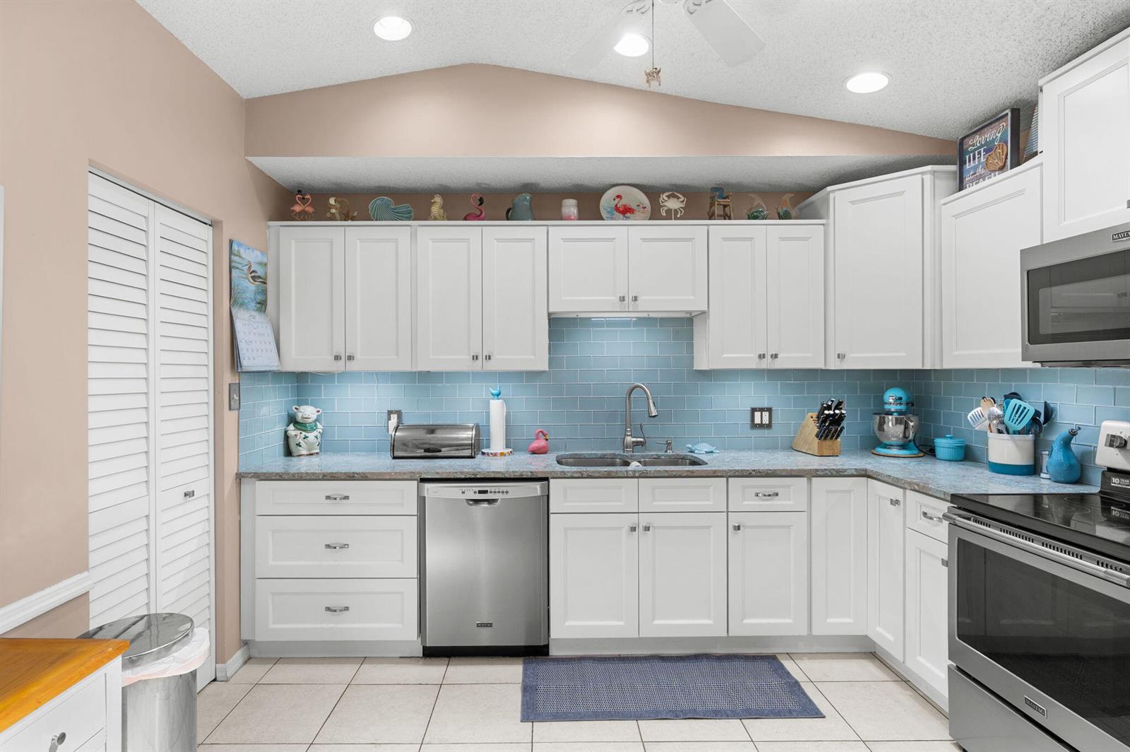 A kitchen features white cabinets, stainless steel appliances, and a light blue subway tile backsplash — 1531 Pheasant Walk # C, Fort Pierce FL 34950, FORT PIERCE, FL