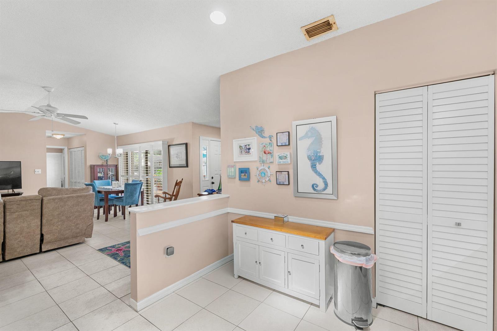 A living room and dining area feature light tile floors, beige walls, and coastal decor — 1531 Pheasant Walk # C, Fort Pierce FL 34950, FORT PIERCE, FL