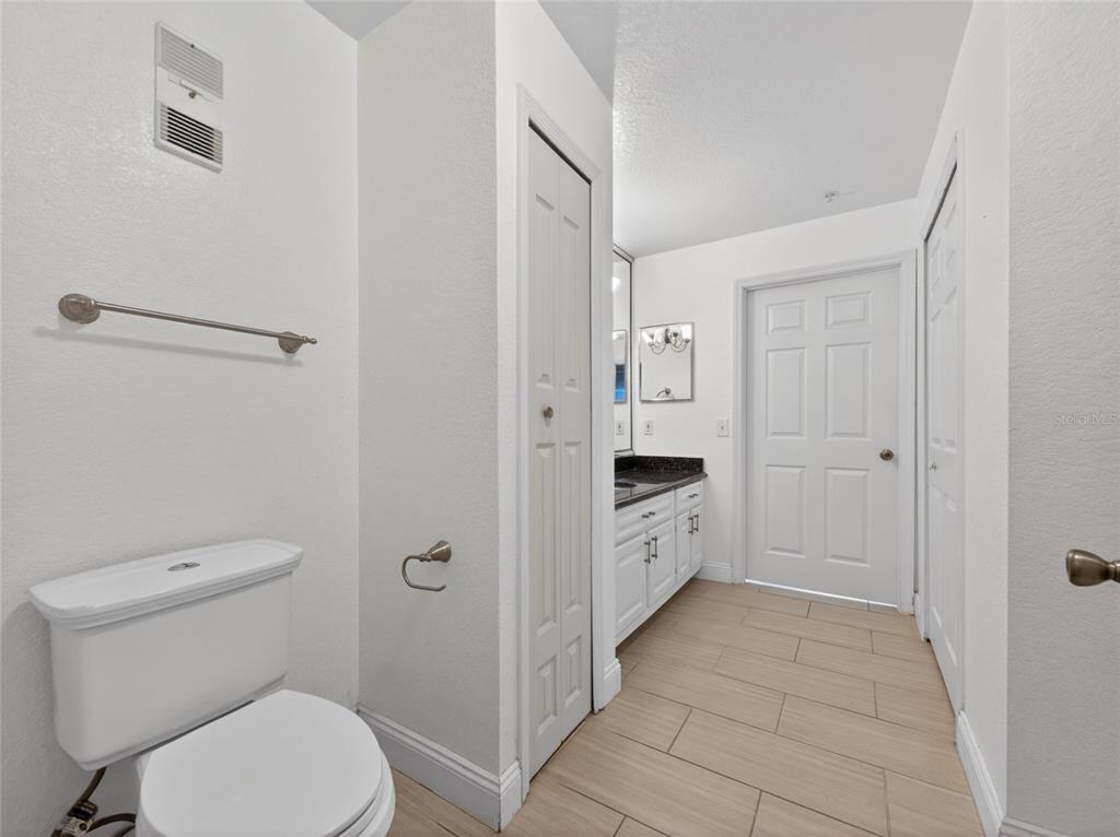 A bathroom features a white toilet, a vanity with a dark countertop, and tiled flooring — 13003 PLANTATION PARK CIRCLE UNIT 1311, ORLANDO, FL