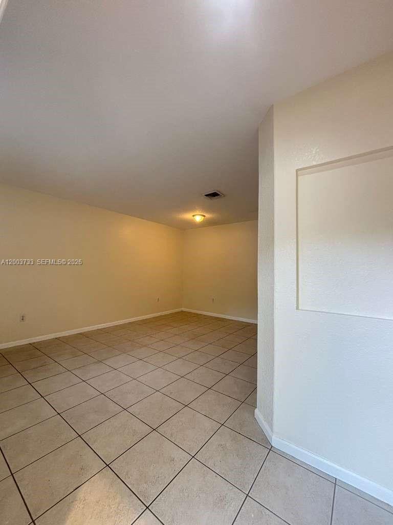 An empty room features beige walls, light-colored tile flooring, and a recessed wall niche — 8375 SW 29th St # 102, Miramar FL 33025, MIRAMAR, FL