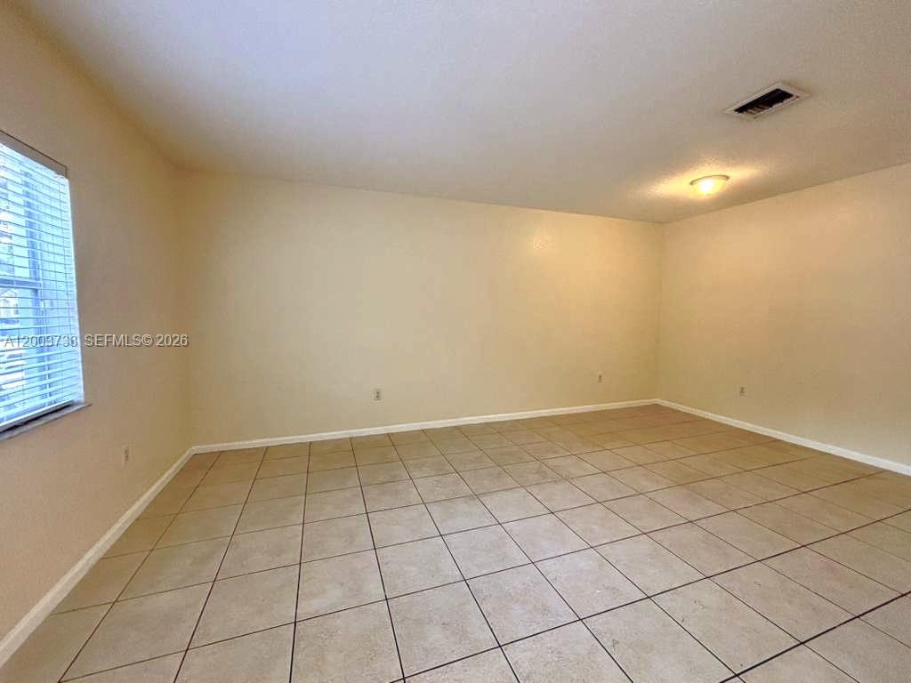 An empty room features beige walls, light-colored tile flooring, and a single ceiling light fixture — 8375 SW 29th St # 102, Miramar FL 33025, MIRAMAR, FL