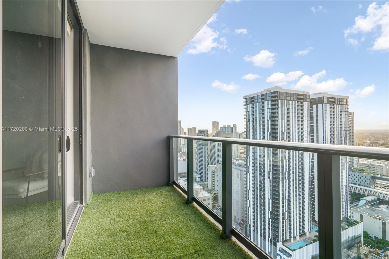 A balcony with artificial turf flooring overlooks a dense urban skyline — 601 NE 1 AVE # 3604, Miami FL 33132, MIAMI, FL