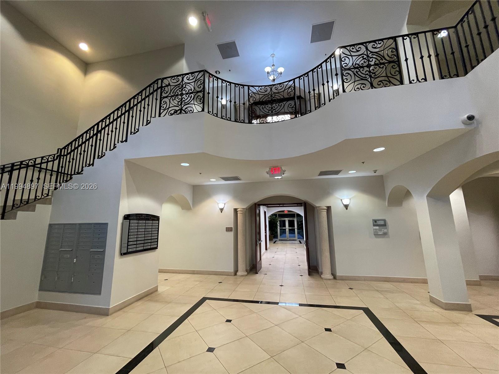 A grand lobby features a curved staircase with ornate iron railings and tiled floors — 2893 Executive Park Dr, Weston FL 33331, WESTON, FL