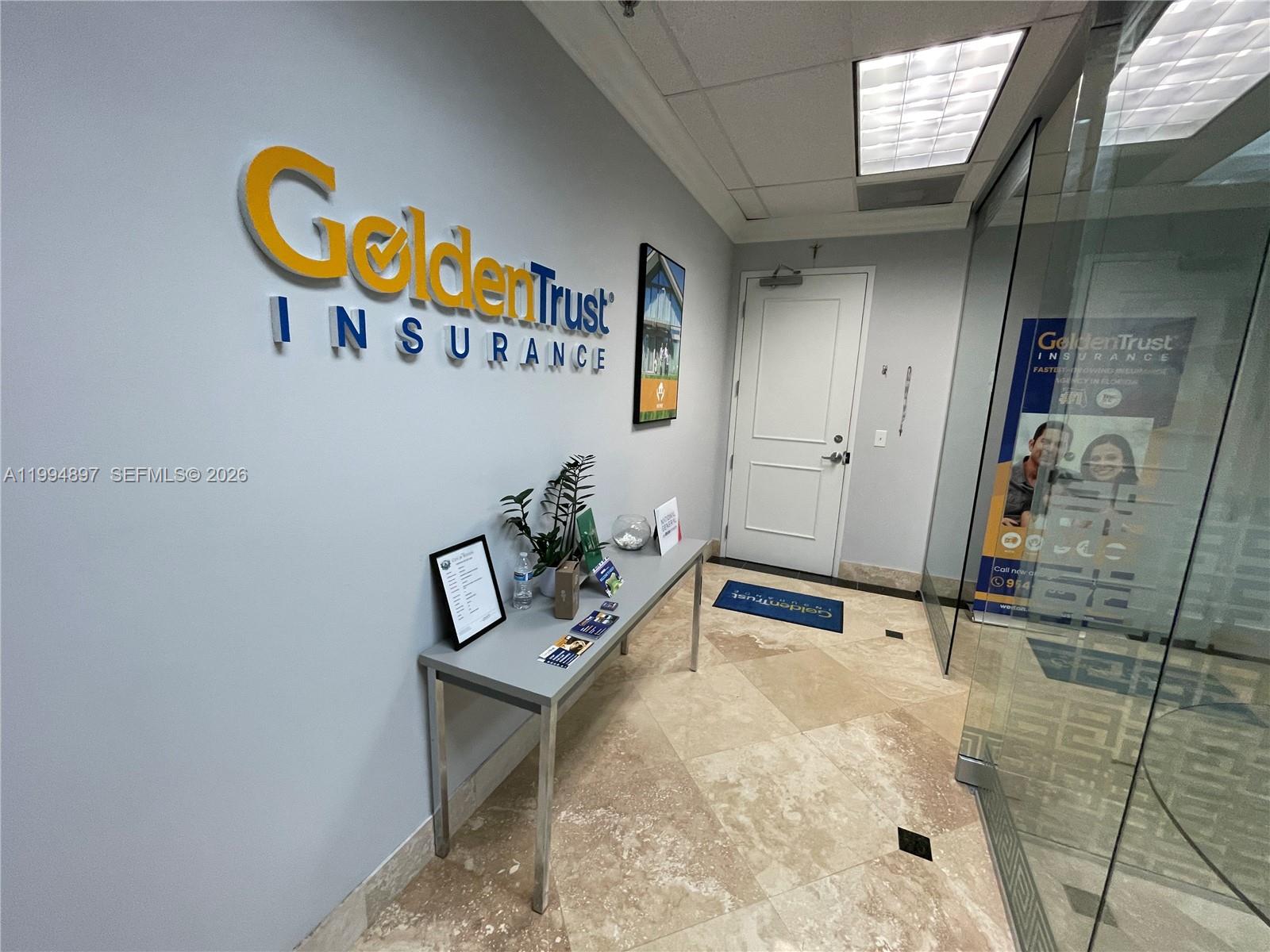 An office reception area features a branded wall, a metal console table, and tile flooring — 2893 Executive Park Dr, Weston FL 33331, WESTON, FL