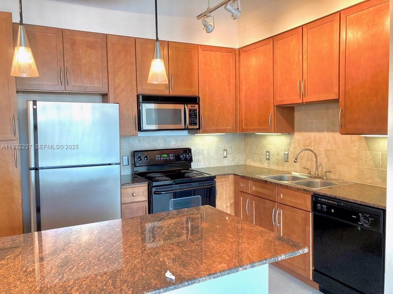 A kitchen features wood cabinets, granite countertops, stainless steel appliances, and a central island — 2001 Biscayne Blvd # 2608, Miami FL 33137, MIAMI, FL