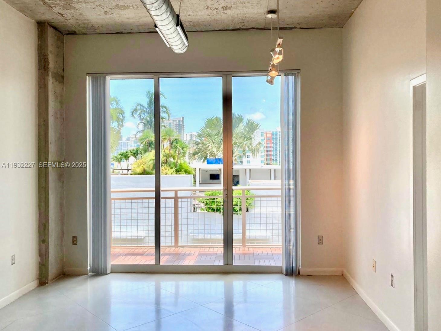 A room with concrete ceilings, tile flooring, and a sliding glass door leading to a balcony — 2001 Biscayne Blvd # 2608, Miami FL 33137, MIAMI, FL