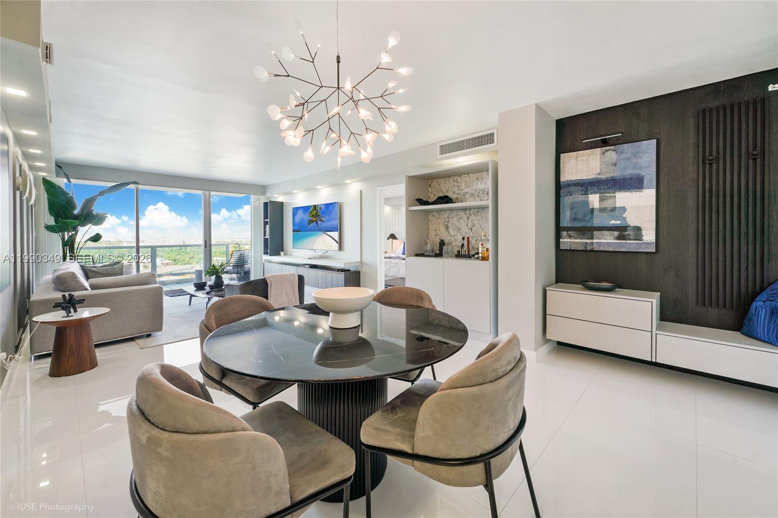 A dining area with a round black table and chairs sits before a living room — 5161 Collins Ave # 1508, Miami Beach FL 33140, MIAMI BEACH, FL