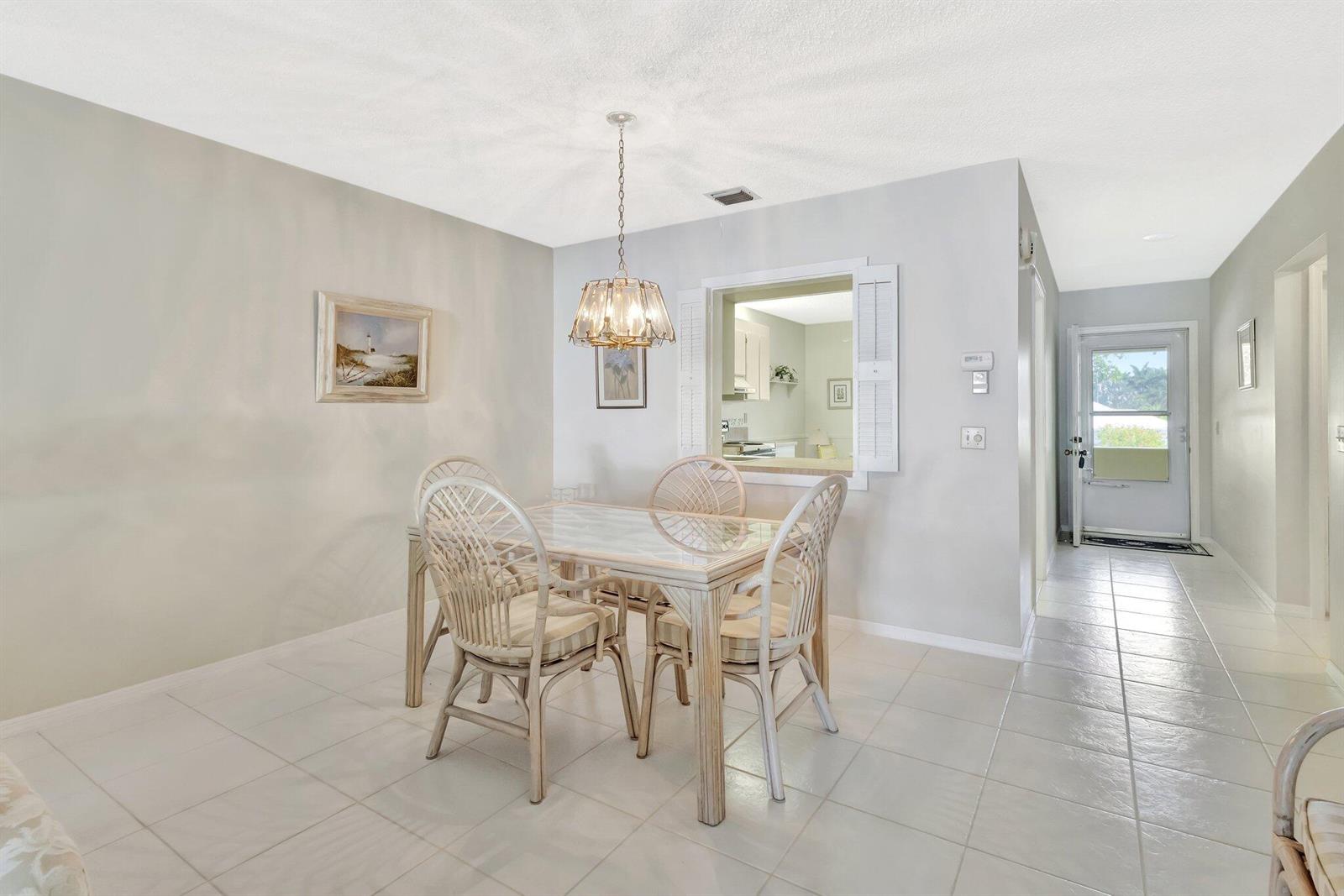 A dining area features a glass-top rattan table, four matching chairs, and a pass-through window — 1600 SE Saint Lucie Boulevard SE # 211, Stuart FL 34996, STUART, FL