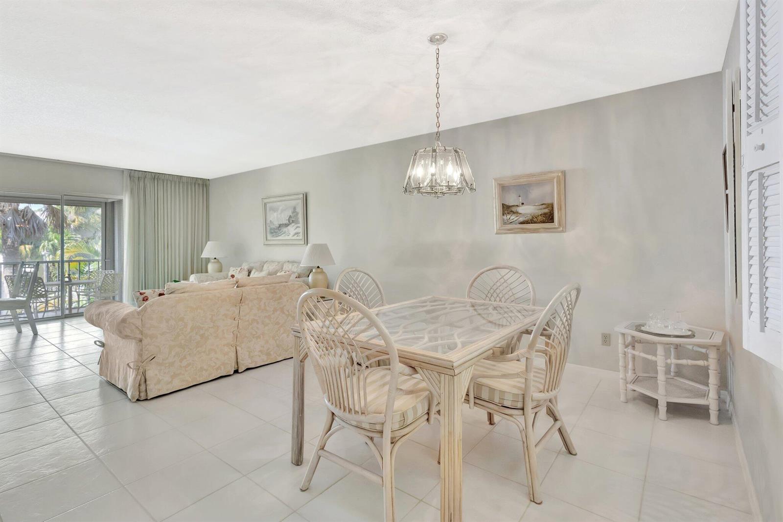 A dining area with a glass-topped table and wicker chairs sits before a living room — 1600 SE Saint Lucie Boulevard SE # 211, Stuart FL 34996, STUART, FL
