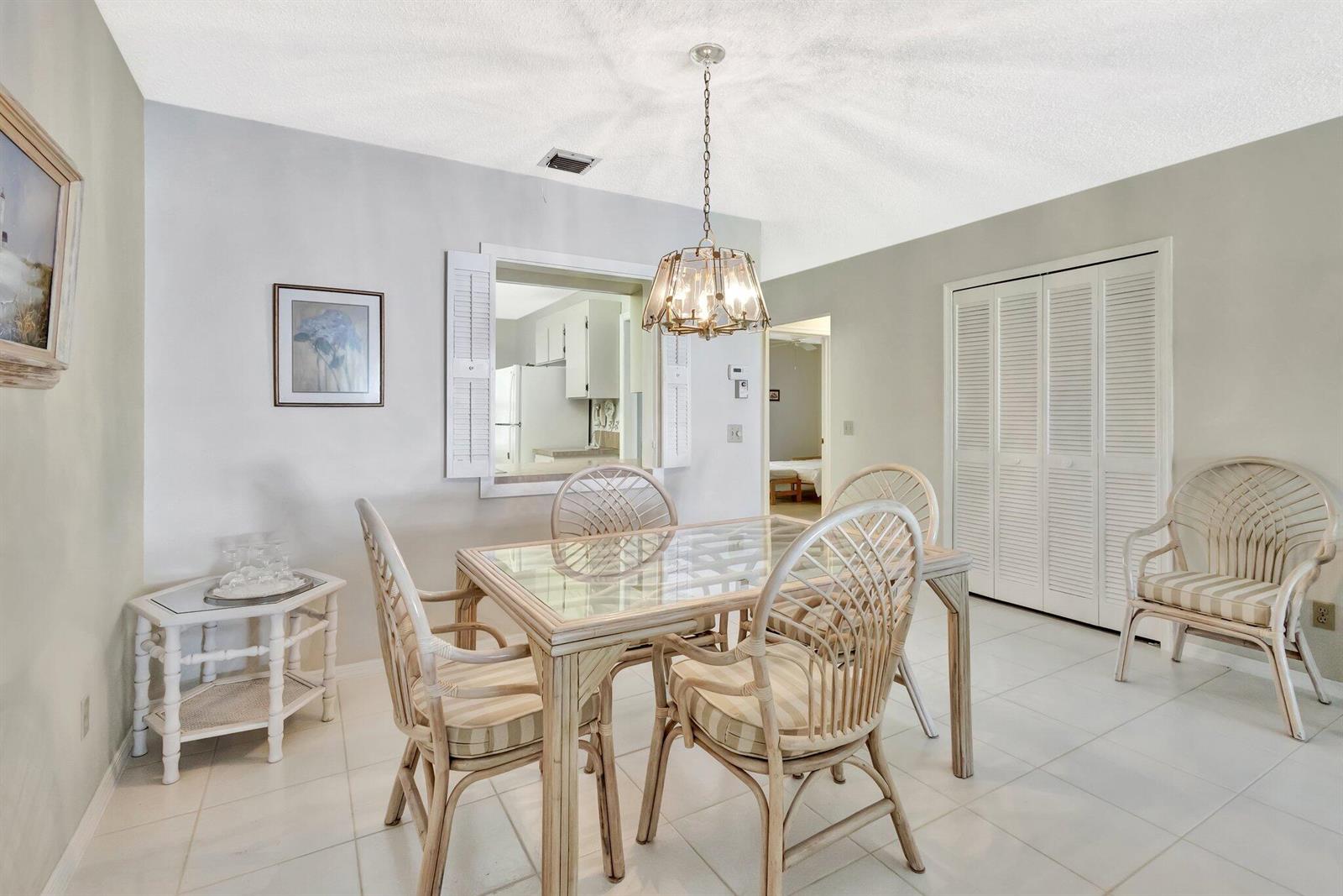 A dining room with a glass-top rattan table, matching chairs, and a pass-through window — 1600 SE Saint Lucie Boulevard SE # 211, Stuart FL 34996, STUART, FL