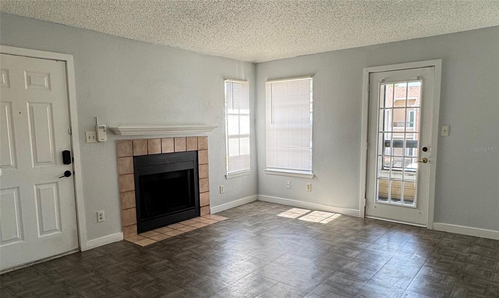 A living room features a fireplace, tile flooring, two windows, and two exterior doors — 5540 DEVONBRIAR WAY UNIT 203, ORLANDO, FL