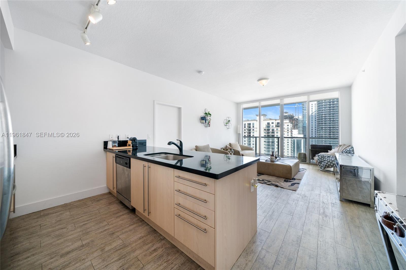 A kitchen island with black countertops sits in an open-concept apartment with floor-to-ceiling windows — 1111 SW 1st Ave, Miami FL 33130, MIAMI, FL