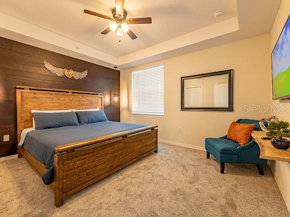 A bedroom features a wooden bed frame, dark accent wall, and a teal armchair — 3120 PARADOX CIRCLE UNIT 108, KISSIMMEE, FL