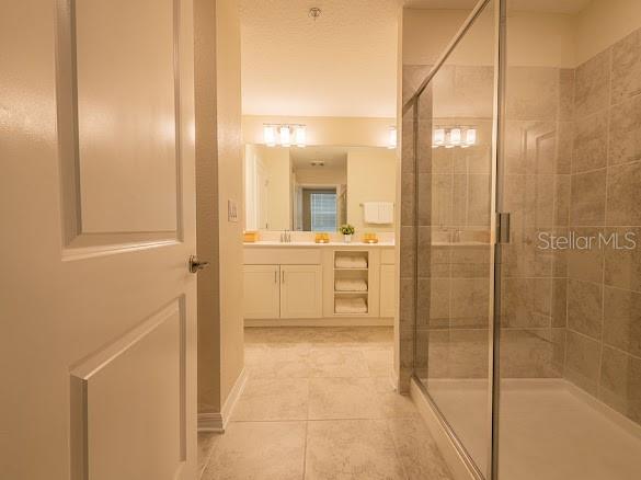 A bathroom features a glass-enclosed shower, a double vanity with white cabinets, and tile flooring — 3120 PARADOX CIRCLE UNIT 108, KISSIMMEE, FL