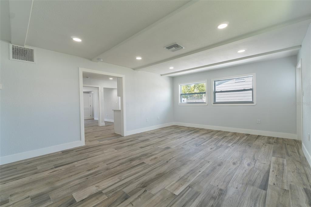 An empty room with light gray walls, wood-look flooring, recessed lighting, and two windows — 116 85TH AVENUE N, ST PETERSBURG, FL