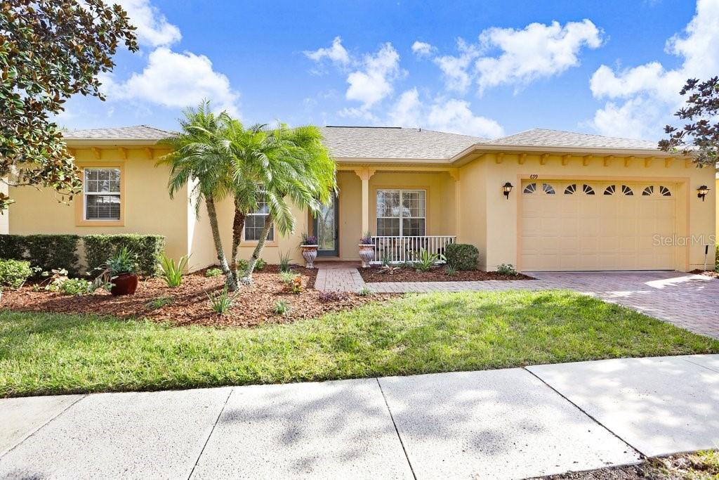 A single-story house with a yellow stucco exterior, a two-car garage, and a palm tree — 699 GLENDORA ROAD, KISSIMMEE, FL