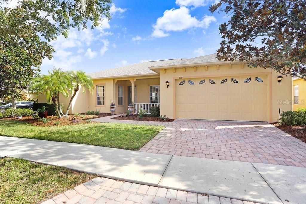A single-story house with a beige stucco exterior, a two-car garage, and a paved driveway — 699 GLENDORA ROAD, KISSIMMEE, FL