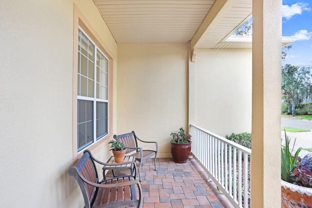 A covered front porch features brick pavers, two wooden benches, and a white railing — 699 GLENDORA ROAD, KISSIMMEE, FL