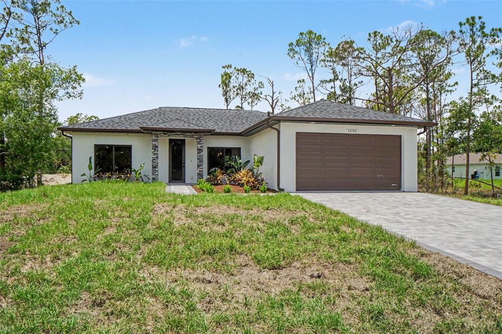 A single-story house with a white stucco exterior, a brown garage door, and a paved driveway — 1059 MADEIRA STREET, PORT CHARLOTTE, FL