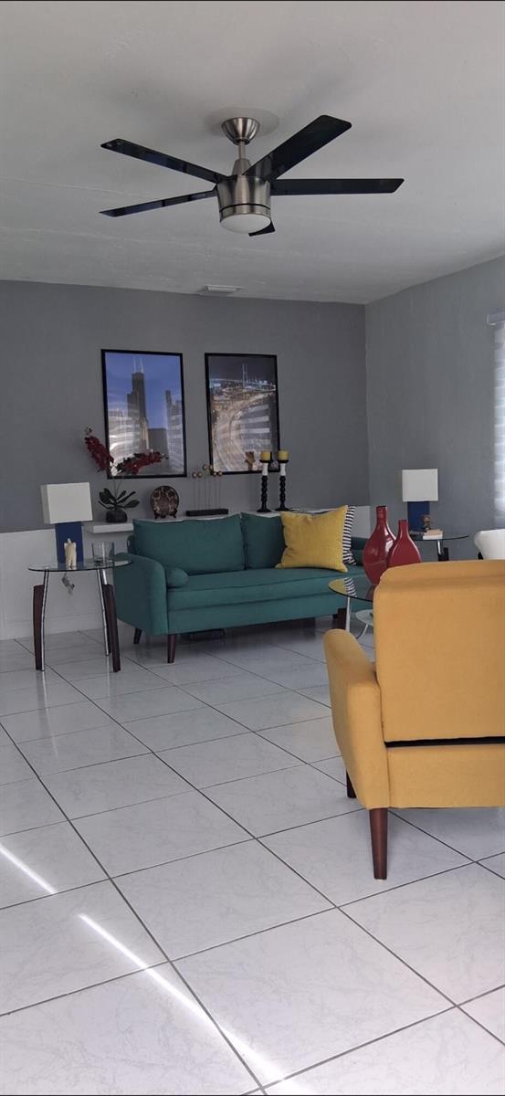 A living room features a teal sofa, a yellow armchair, and gray walls with tile flooring — 1519 S 24th Terrace, Hollywood FL 33020, HOLLYWOOD, FL