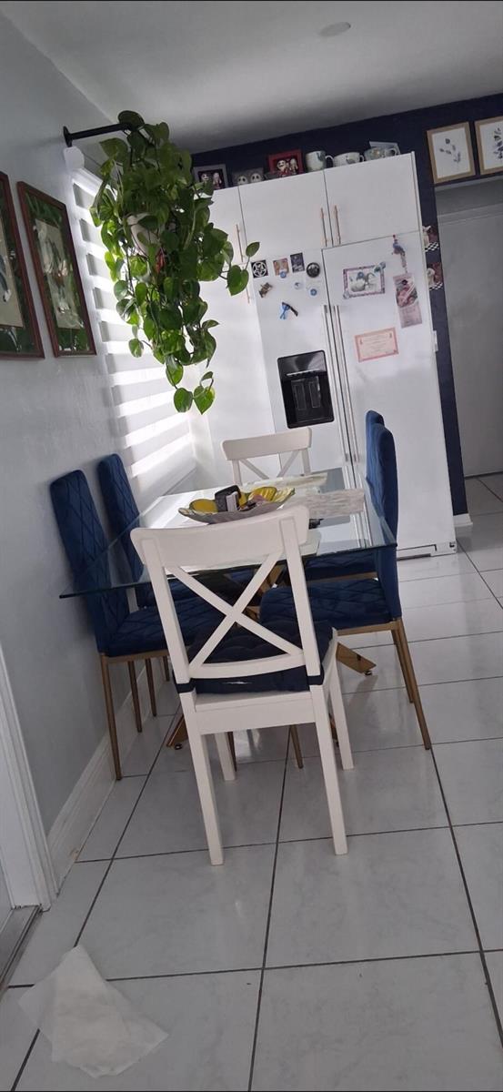 A dining area features a glass table, blue upholstered chairs, and a hanging green plant — 1519 S 24th Terrace, Hollywood FL 33020, HOLLYWOOD, FL