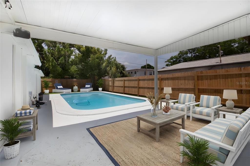 A covered patio overlooks a backyard swimming pool with lounge chairs and outdoor furniture — 3459 8TH AVENUE N, ST PETERSBURG, FL