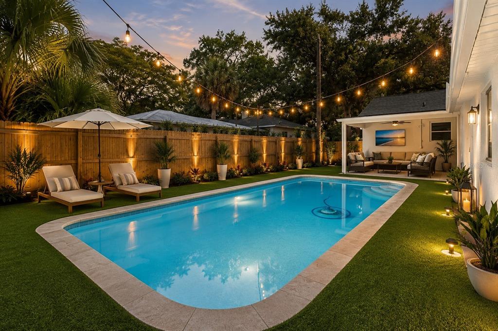 A backyard features a rectangular swimming pool, lounge chairs, a covered patio, and string lights — 3459 8TH AVENUE N, ST PETERSBURG, FL