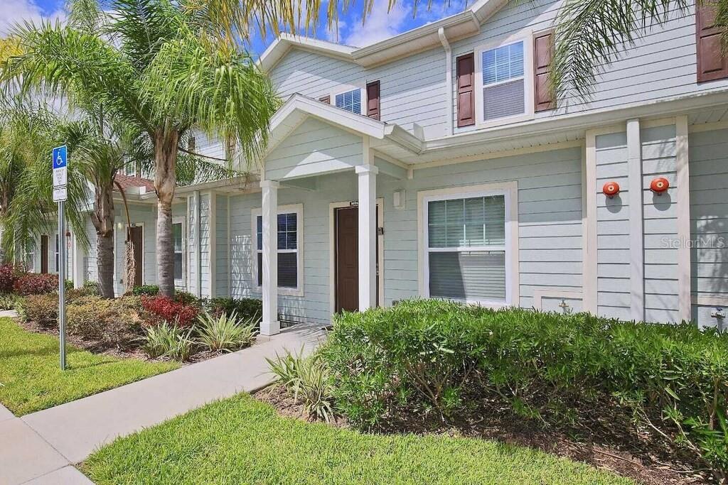A two-story light blue building with a covered entryway, palm trees, and a sidewalk — 8905 SHINE DRIVE, KISSIMMEE, FL