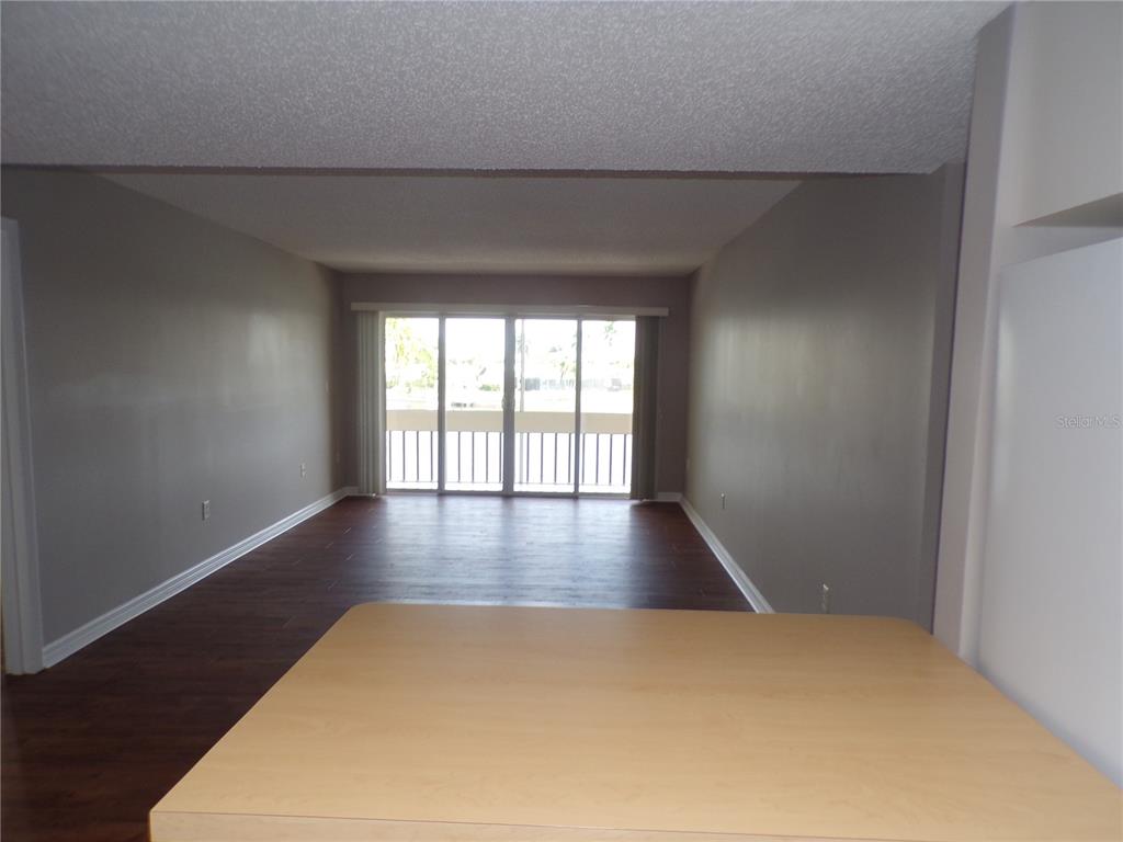A view from a kitchen counter looking into an empty living room with sliding doors — 1080 BAL HARBOR BOULEVARD UNIT 4D, PUNTA GORDA, FL