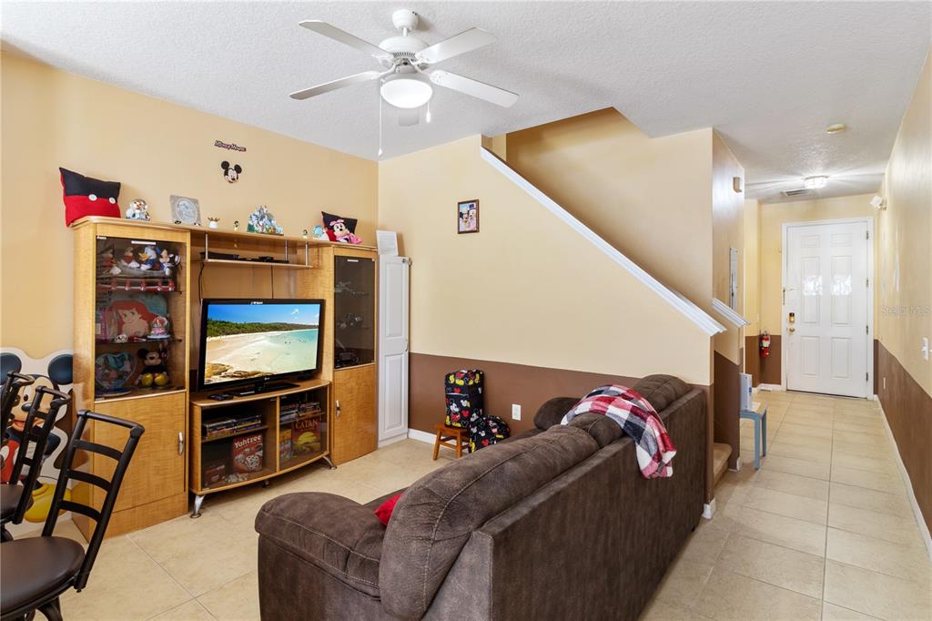 A living room features a brown sofa, a wooden entertainment center, and a ceiling fan — 7646 LONG ISLAND DRIVE, KISSIMMEE, FL