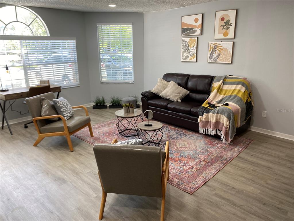 A living room features a dark leather sofa, two armchairs, a patterned rug, and artwork — 2723 N POINCIANA BOULEVARD UNIT 159, KISSIMMEE, FL