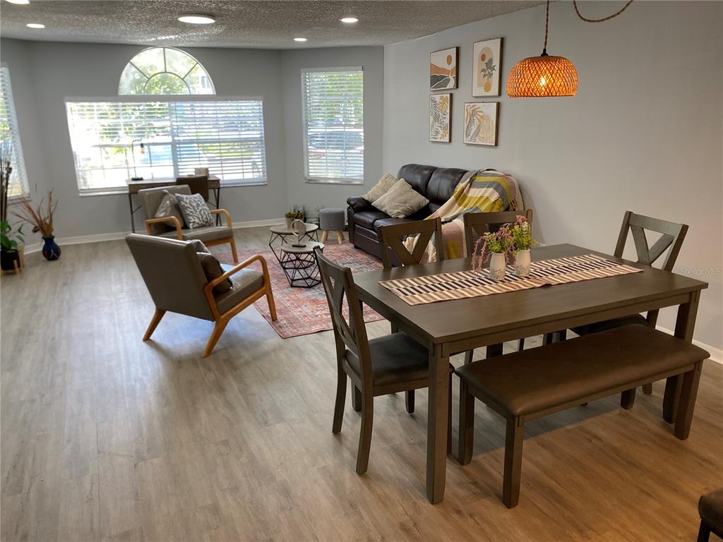 An open-concept living and dining area features wood-look flooring, a dark sofa, and a table — 2723 N POINCIANA BOULEVARD UNIT 159, KISSIMMEE, FL