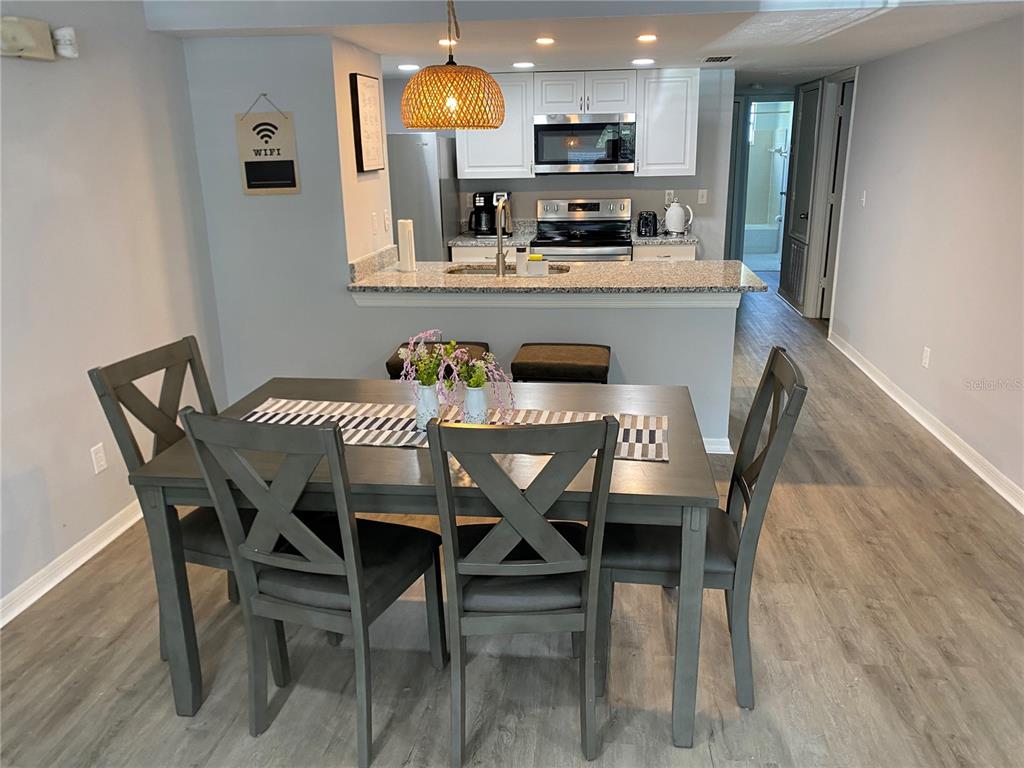A dining area with a grey table and chairs sits in front of an open kitchen — 2723 N POINCIANA BOULEVARD UNIT 159, KISSIMMEE, FL