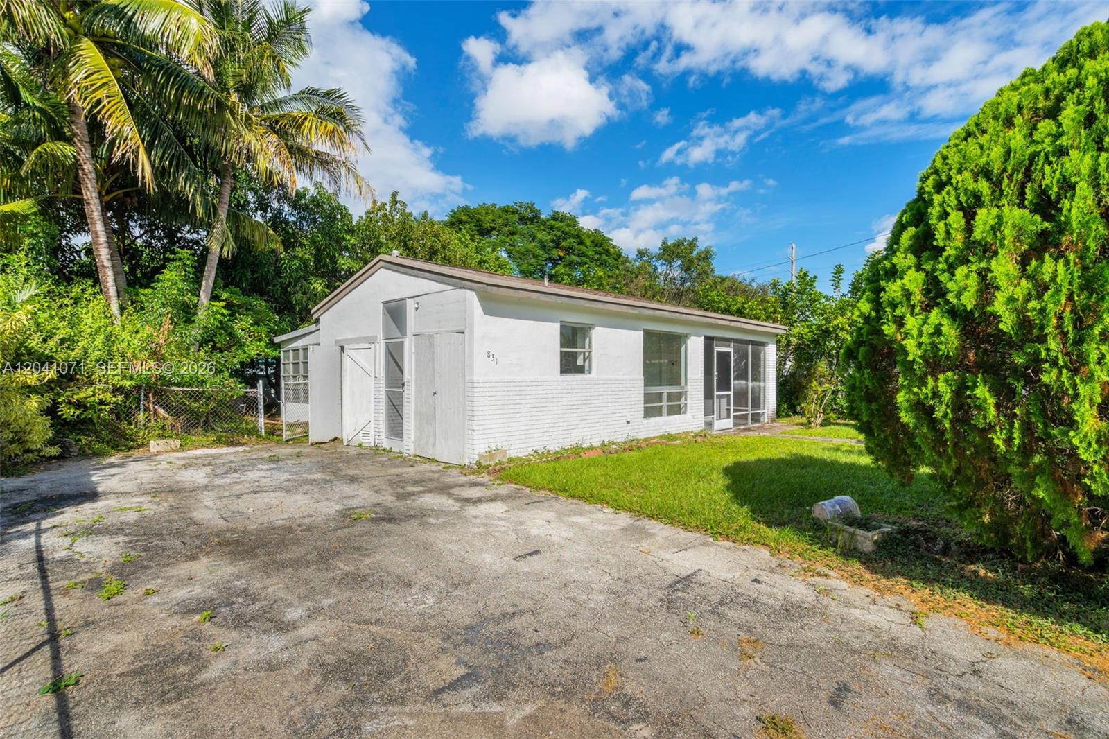 A white, single-story house with a concrete driveway and a large green tree — 6831 Greene St # 6831, Hollywood FL 33024, HOLLYWOOD, FL