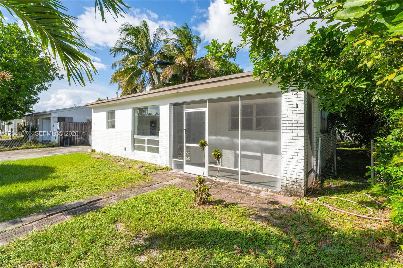 A white brick house features a screened-in porch and a paved walkway in the yard — 6831 Greene St # 6831, Hollywood FL 33024, HOLLYWOOD, FL