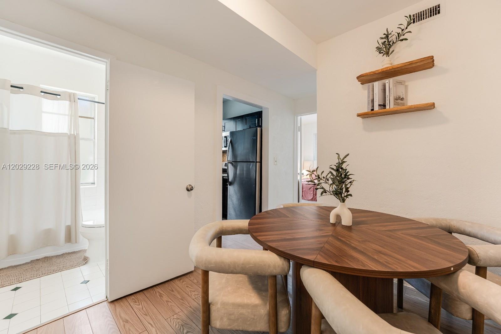 A dining area with a round wooden table, upholstered chairs, and wall-mounted shelving — 301 SW 10th Ave # 2, Miami FL 33130, MIAMI, FL