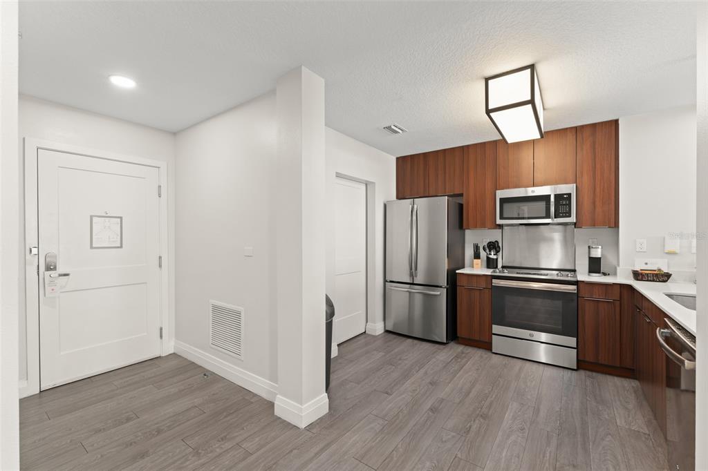 A kitchen with wood cabinets, stainless steel appliances, and gray wood-look flooring — 14501 GROVE RESORT AVENUE UNIT 2334, WINTER GARDEN, FL