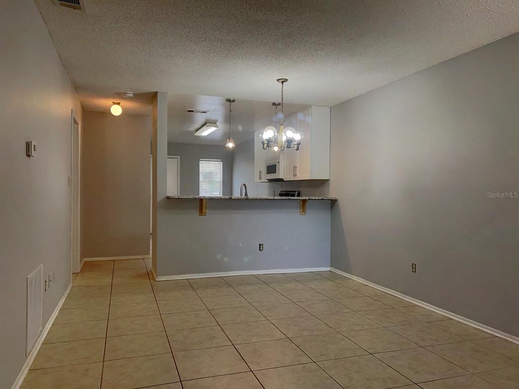 A dining area with tile flooring features a breakfast bar opening into a kitchen — 1421 SOPHIE BOULEVARD, ORLANDO, FL