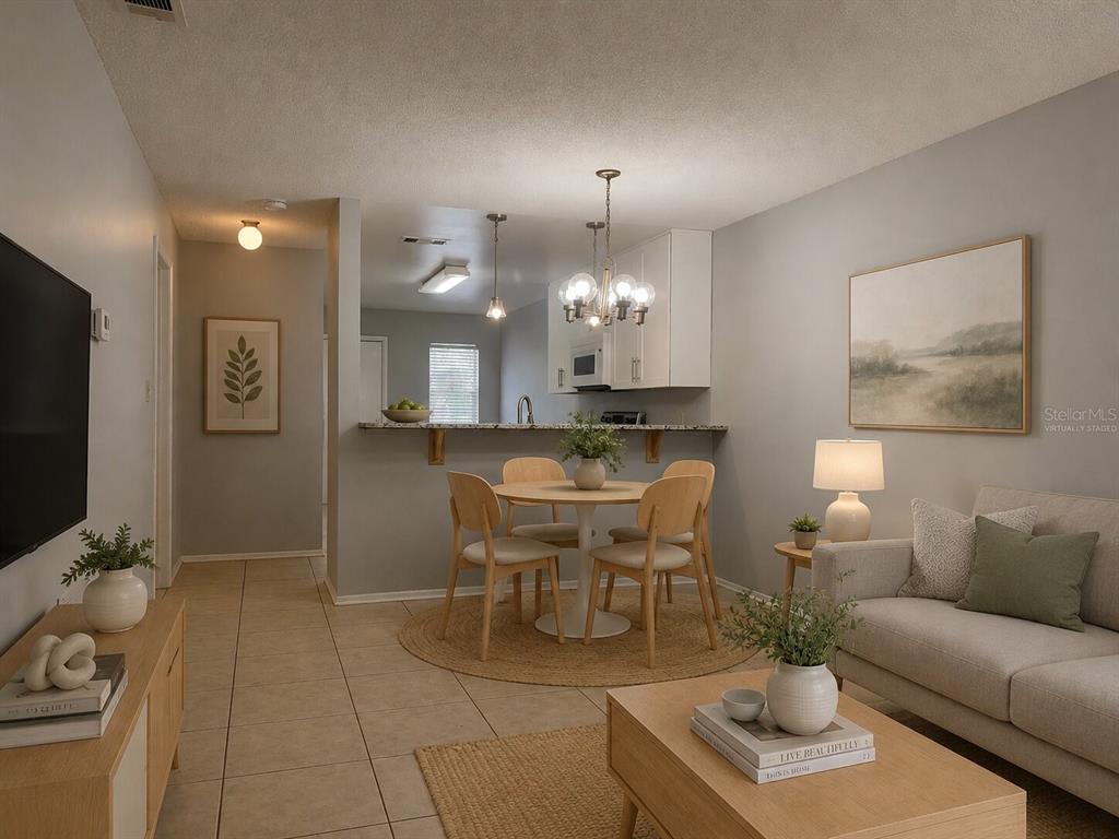 A living and dining area with tile floors, a round table, and a neutral sofa — 1421 SOPHIE BOULEVARD, ORLANDO, FL