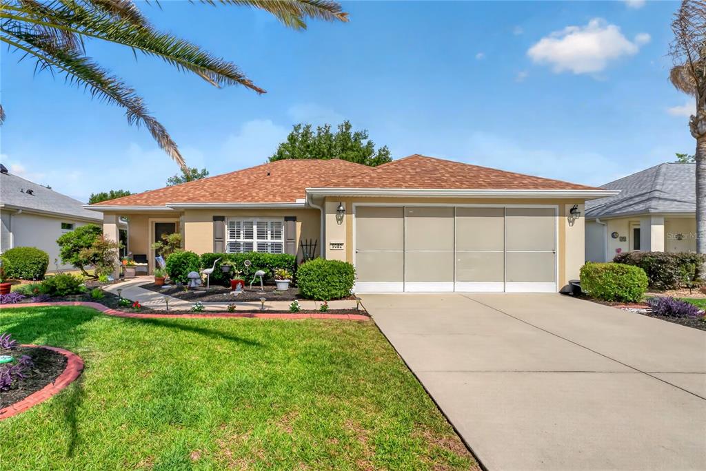A single-story house with a tan exterior, a brown shingled roof, and a concrete driveway — 9082 SE 120TH LOOP, SUMMERFIELD, FL