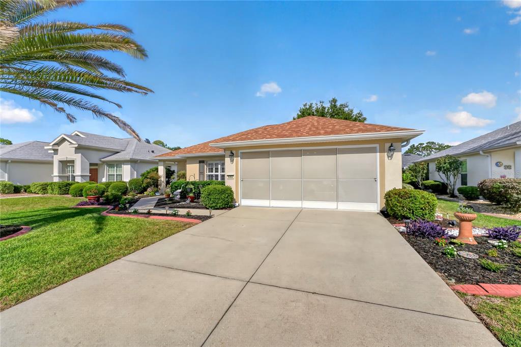 A single-story house with a tan exterior, a brown roof, and a concrete driveway — 9082 SE 120TH LOOP, SUMMERFIELD, FL