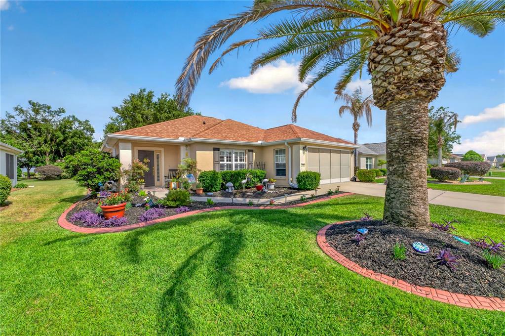 A single-story house with a tan exterior, a palm tree, and a landscaped front yard — 9082 SE 120TH LOOP, SUMMERFIELD, FL