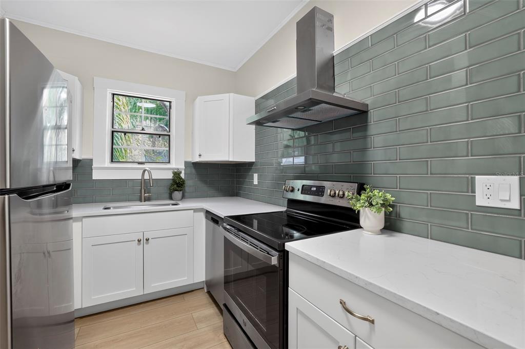A kitchen features white cabinets, a stainless steel stove, and a green subway tile backsplash — 813 E NEW ORLEANS AVENUE, TAMPA, FL