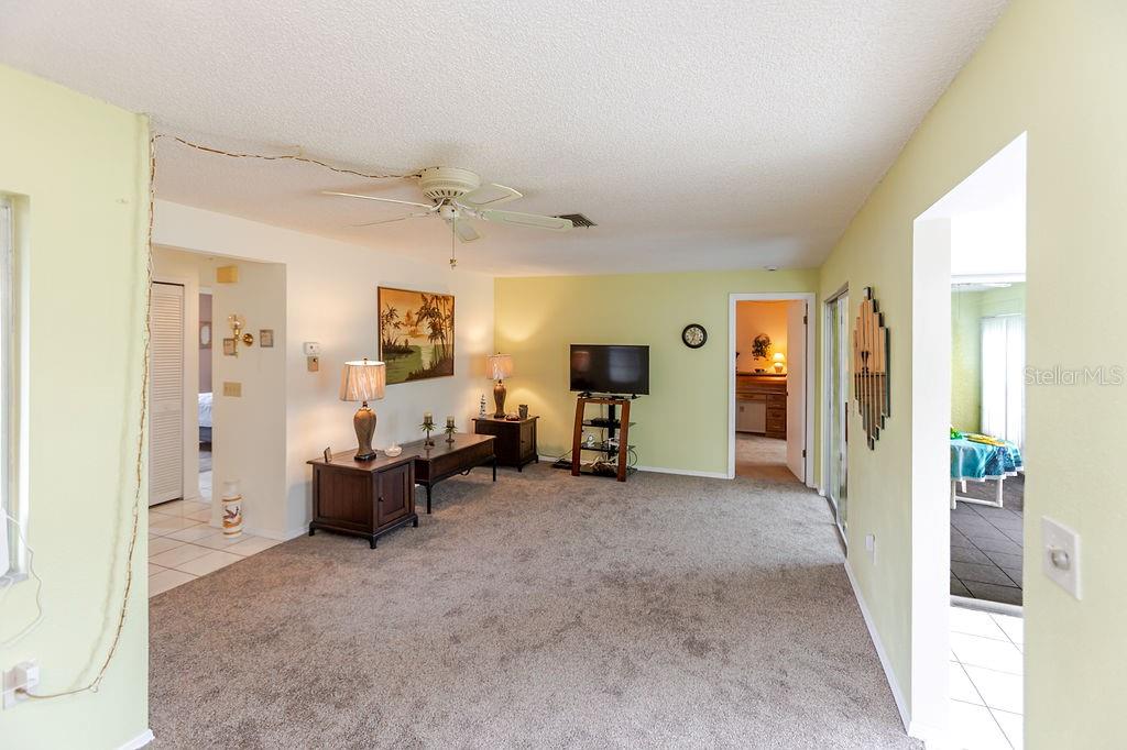 A living room with light green walls, gray carpeting, a ceiling fan, and multiple doorways — 7560 ST ANDREWS BOULEVARD UNIT 7560, WEEKI WACHEE, FL