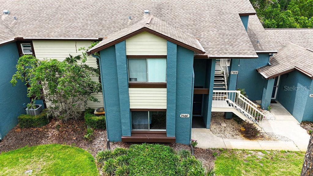 An exterior view of a two-story apartment building with teal and beige siding — 7560 ST ANDREWS BOULEVARD UNIT 7560, WEEKI WACHEE, FL